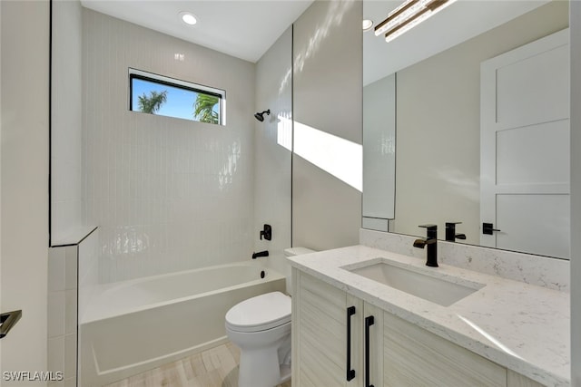 full bathroom with vanity, hardwood / wood-style floors, tiled shower / bath combo, and toilet