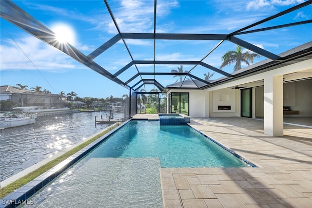 view of swimming pool featuring an in ground hot tub, a water view, glass enclosure, and a patio area