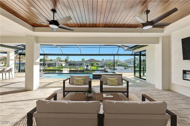 view of patio / terrace featuring glass enclosure, ceiling fan, a bar, and an outdoor hangout area