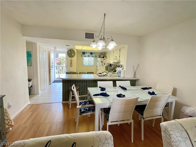 dining area featuring light hardwood / wood-style flooring and a chandelier