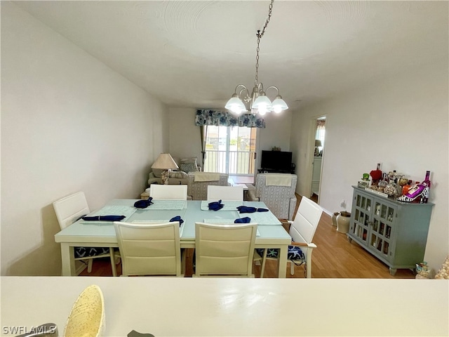 dining area with light wood-type flooring and a notable chandelier