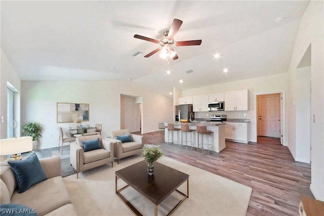 living room featuring ceiling fan, light hardwood / wood-style floors, and lofted ceiling