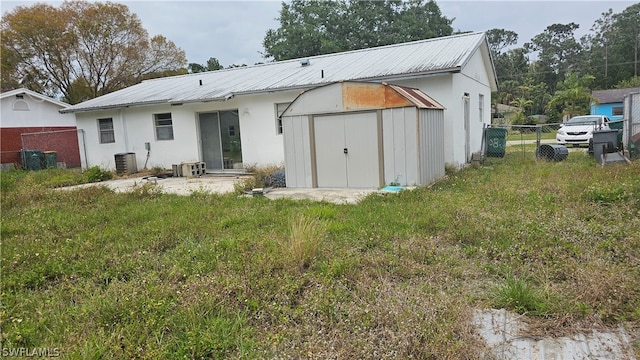 rear view of house featuring a shed, central air condition unit, and a yard