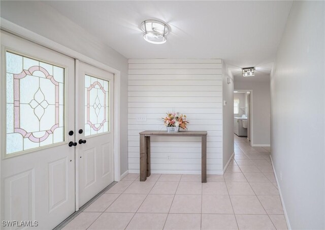 foyer with wood walls, french doors, and light tile patterned floors