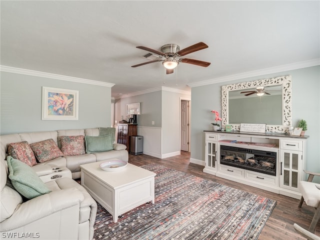 living room with a ceiling fan, crown molding, baseboards, and wood finished floors