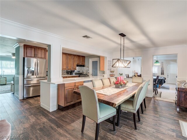 dining area featuring ceiling fan, visible vents, dark wood-type flooring, and ornamental molding