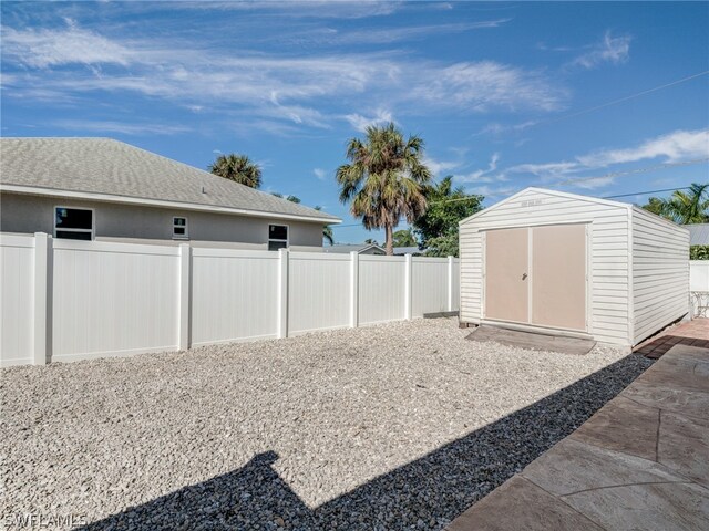 view of yard featuring a fenced backyard, a storage unit, and an outbuilding