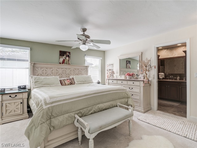 bedroom featuring light carpet, baseboards, a ceiling fan, and connected bathroom