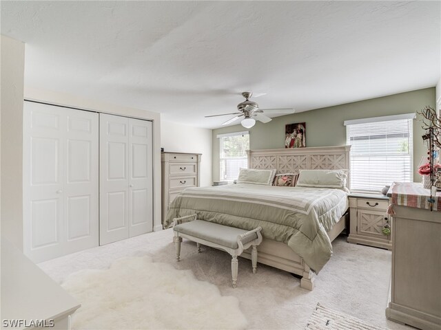 bedroom with ceiling fan, a closet, and light colored carpet