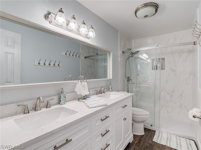 full bath featuring toilet, wood tiled floor, a marble finish shower, and a sink