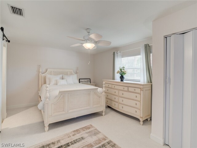 bedroom with light colored carpet, visible vents, a barn door, ceiling fan, and baseboards