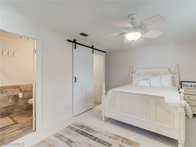 bedroom with a ceiling fan, a barn door, visible vents, and connected bathroom