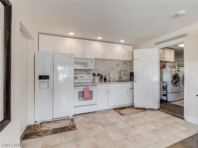 kitchen with white appliances, a sink, white cabinets, independent washer and dryer, and tasteful backsplash