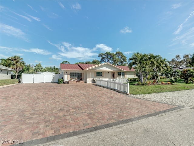 ranch-style house with a fenced front yard, decorative driveway, a gate, metal roof, and a front lawn