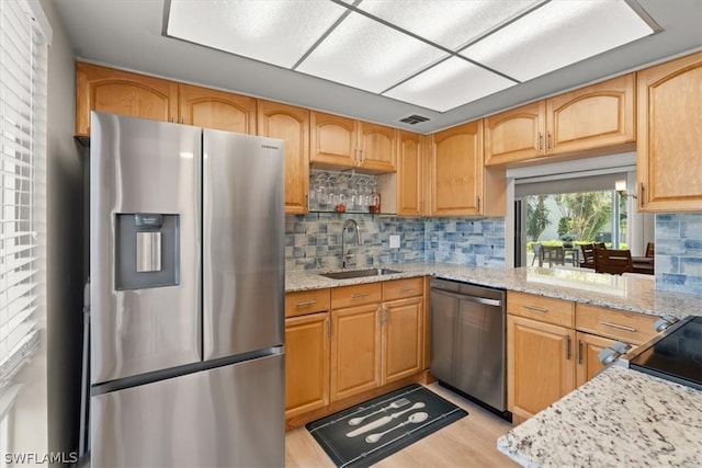 kitchen featuring tasteful backsplash, light hardwood / wood-style floors, stainless steel appliances, and sink