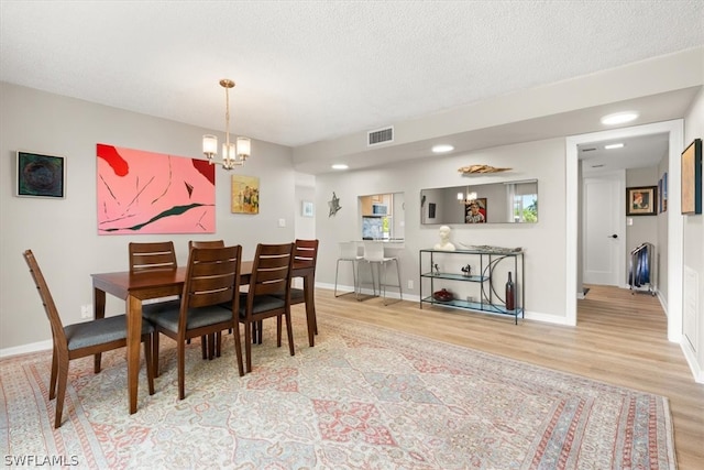 dining room featuring hardwood / wood-style floors, a textured ceiling, and an inviting chandelier