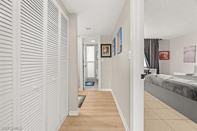 corridor featuring a textured ceiling and light hardwood / wood-style floors