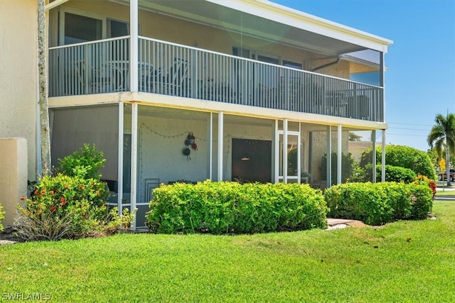 back of house featuring a balcony and a lawn