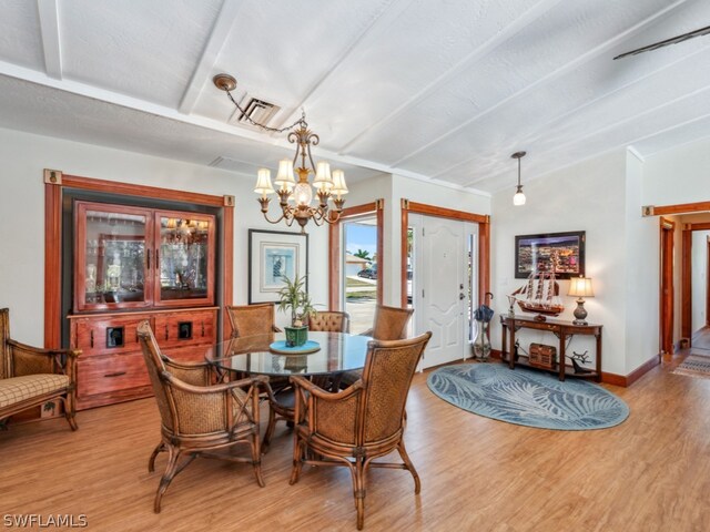 dining room featuring a textured ceiling, vaulted ceiling, light wood-type flooring, and an inviting chandelier