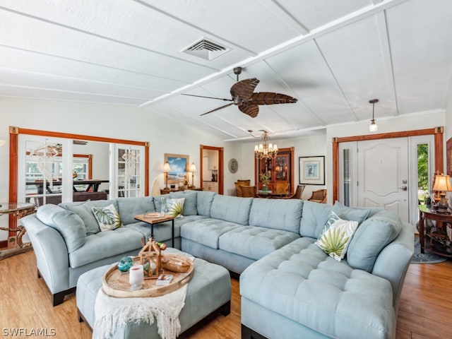 living room featuring vaulted ceiling, light hardwood / wood-style flooring, and ceiling fan with notable chandelier