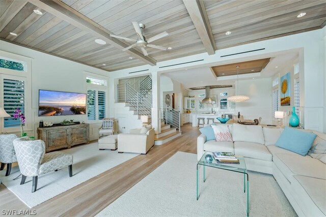 living room with beamed ceiling, light hardwood / wood-style flooring, and ceiling fan