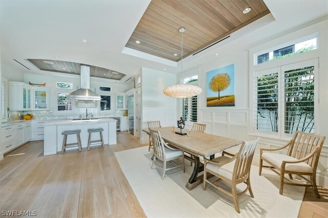 dining space with wooden ceiling, light hardwood / wood-style floors, a raised ceiling, and sink