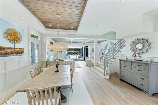 dining room featuring wooden ceiling, a raised ceiling, light hardwood / wood-style floors, and ornate columns