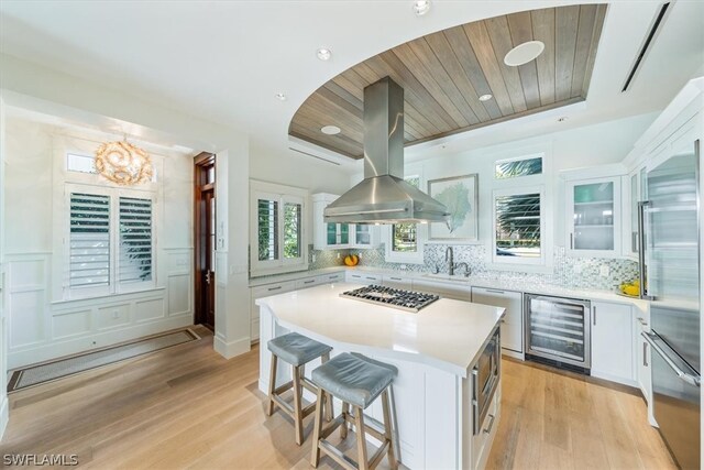 kitchen featuring island exhaust hood, light hardwood / wood-style flooring, backsplash, and a kitchen island