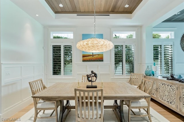 dining room with wooden ceiling, light hardwood / wood-style flooring, a tray ceiling, and a notable chandelier