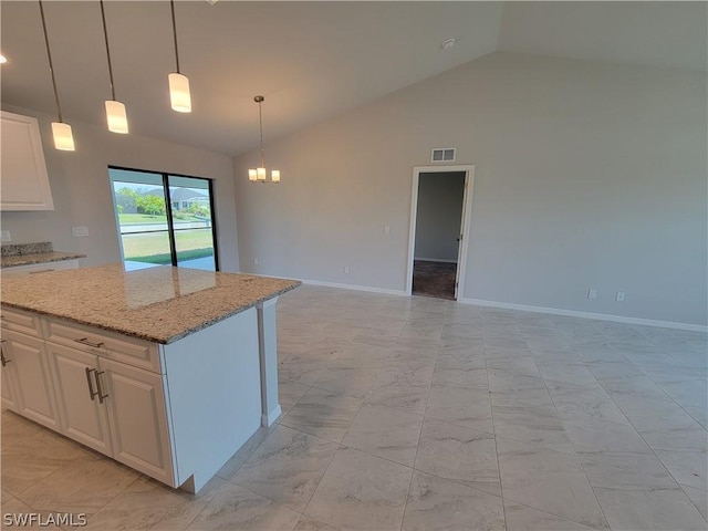 kitchen with white cabinets, a center island, decorative light fixtures, and light stone counters