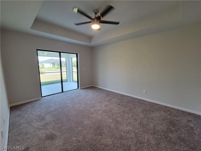 carpeted empty room featuring ceiling fan and a raised ceiling