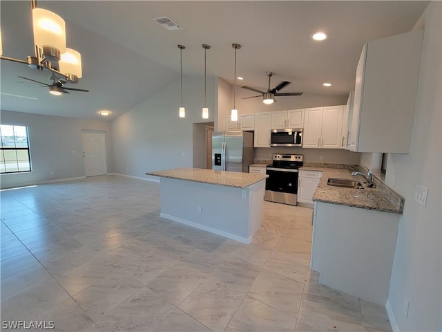 kitchen featuring white cabinetry, sink, stainless steel appliances, lofted ceiling, and decorative light fixtures