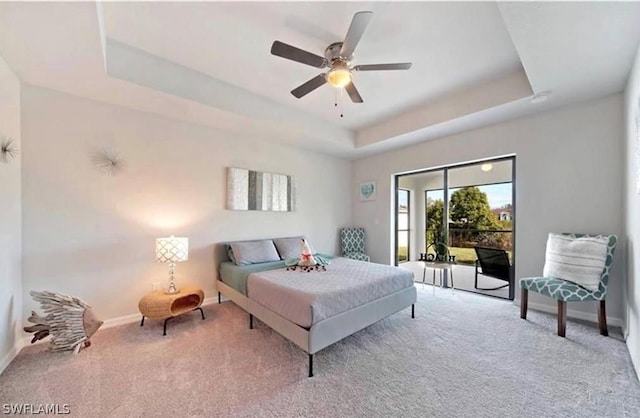 carpeted bedroom with ceiling fan and a raised ceiling