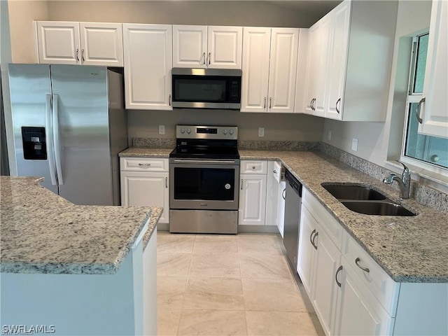 kitchen featuring light stone countertops, appliances with stainless steel finishes, white cabinetry, and sink