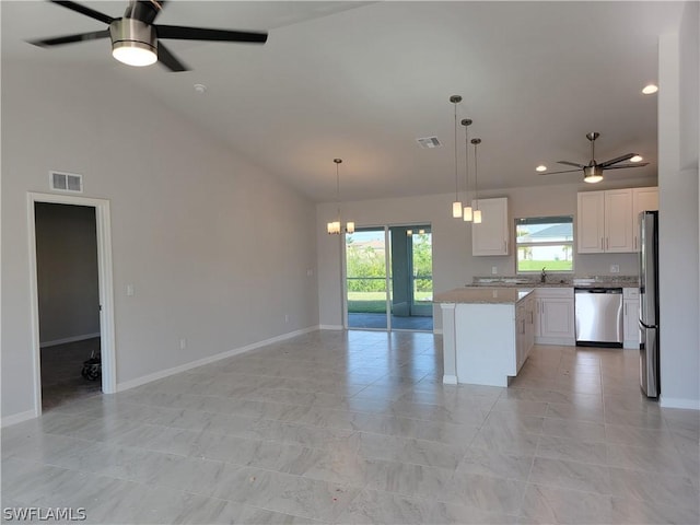 kitchen with light stone countertops, white cabinetry, a center island, stainless steel appliances, and decorative light fixtures