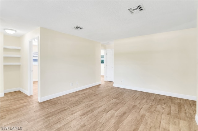 empty room featuring light hardwood / wood-style flooring and a textured ceiling