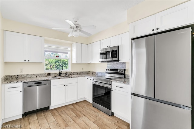 kitchen with white cabinets, sink, stainless steel appliances, and light stone counters