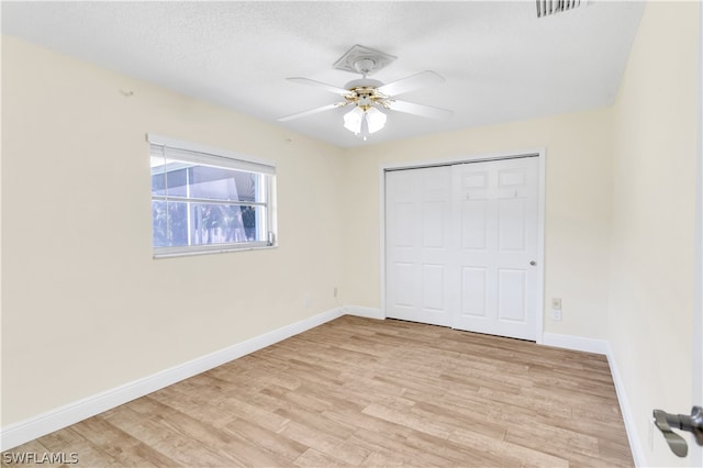 unfurnished bedroom featuring a closet, light hardwood / wood-style flooring, and ceiling fan