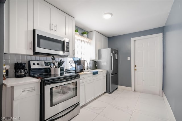 kitchen featuring appliances with stainless steel finishes, white cabinetry, sink, light tile patterned floors, and decorative backsplash