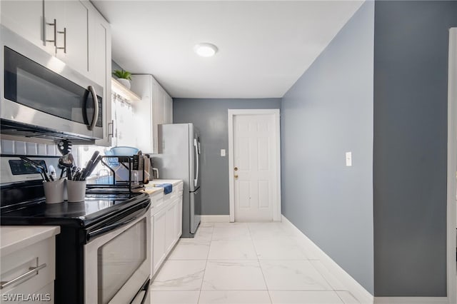 kitchen with appliances with stainless steel finishes, white cabinetry, and light tile patterned floors