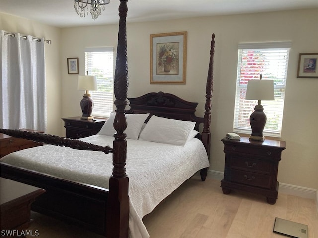 bedroom featuring light hardwood / wood-style floors, multiple windows, and an inviting chandelier