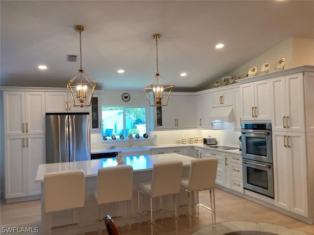 kitchen with a center island, custom exhaust hood, white cabinetry, hanging light fixtures, and stainless steel appliances