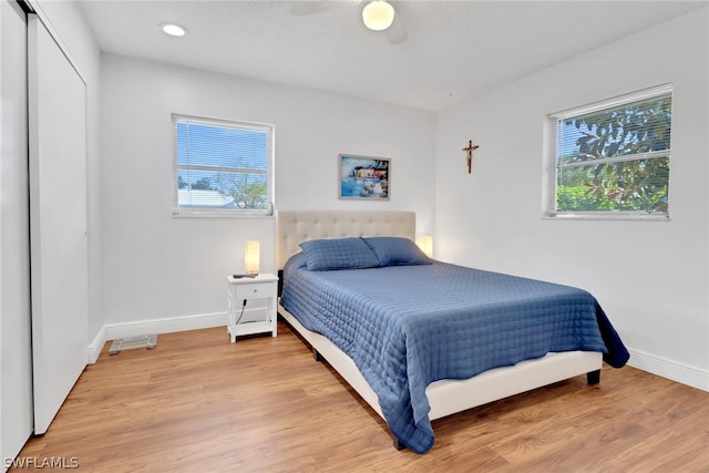 bedroom with ceiling fan, hardwood / wood-style flooring, a closet, and multiple windows