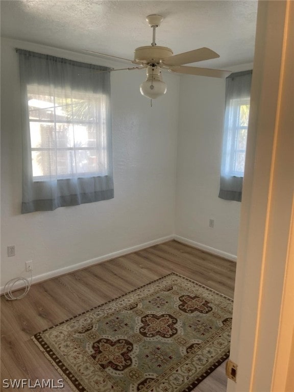 spare room with a textured ceiling, ceiling fan, and light wood-type flooring