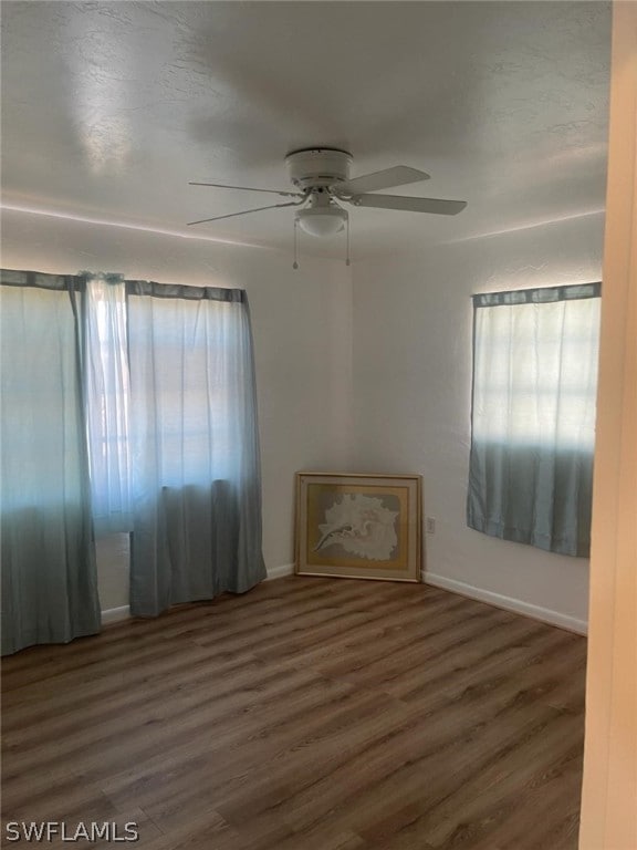 unfurnished room featuring ceiling fan and dark wood-type flooring