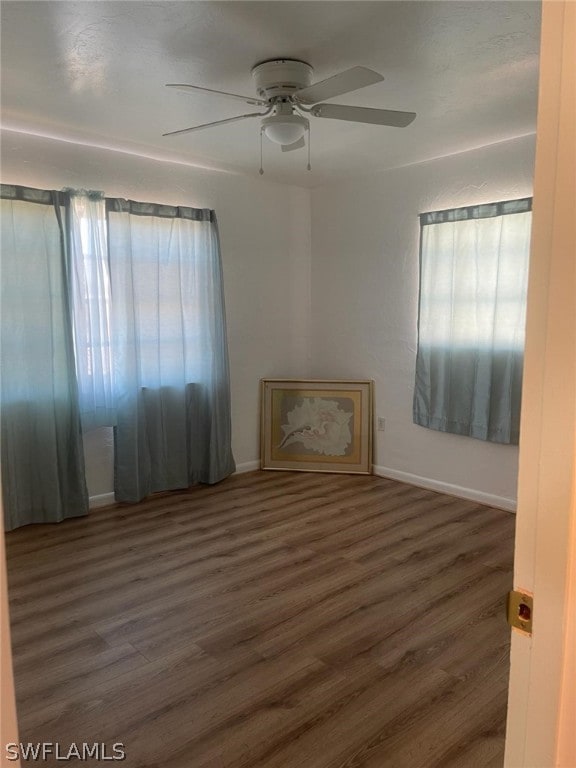 spare room featuring a healthy amount of sunlight, dark hardwood / wood-style floors, and ceiling fan