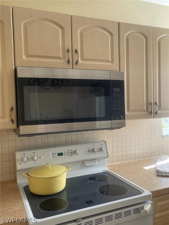 kitchen with tasteful backsplash, light brown cabinets, and white electric range oven