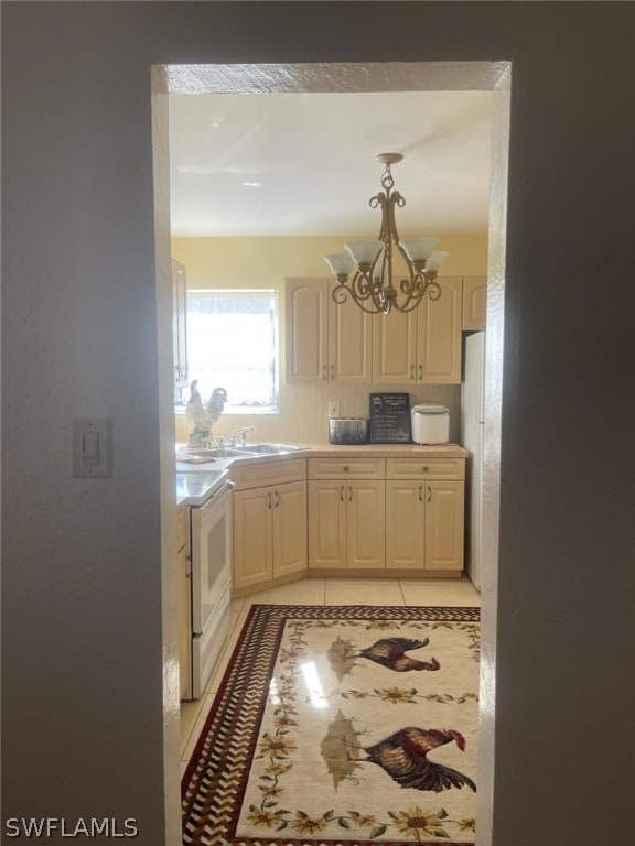 kitchen with white fridge, light tile floors, stove, sink, and a chandelier