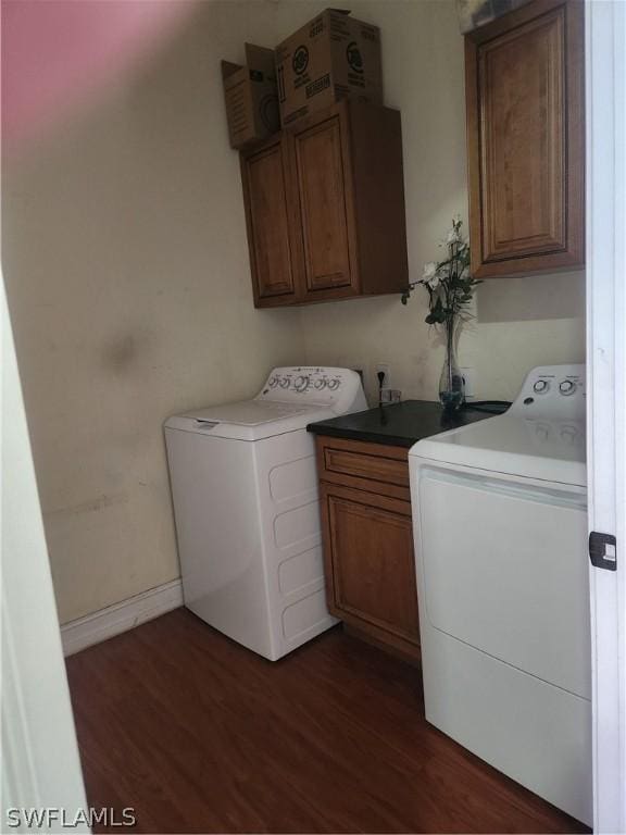 laundry area featuring cabinets, dark hardwood / wood-style flooring, and washing machine and clothes dryer