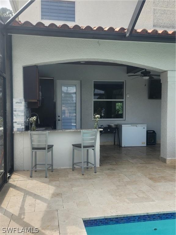 exterior space featuring ceiling fan, a lanai, and a bar